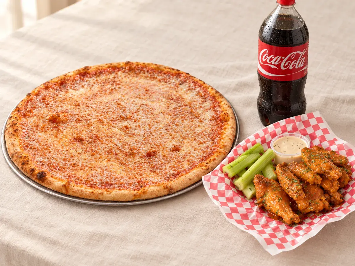 A large cheese pizza, a basket of wings with celery and a bottle of soda